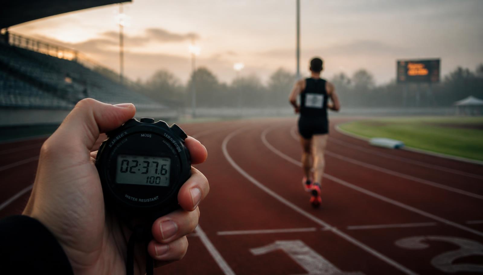 Stoppuhr vor einem Läufer auf der Tartanbahn beim 1.000-Meter-Lauf